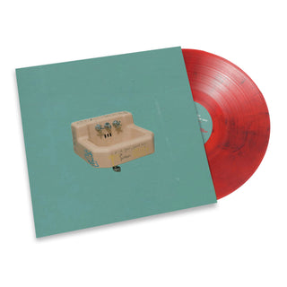 A vinyl record album with a turquoise cover featuring a sink illustration and a red sticker, shown with a translucent red vinyl record partially pulled from the sleeve on a white background.