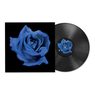 A vinyl record partially pulled from its sleeve, showing a black record with a blue rose center label next to a black album cover featuring a large blue rose on a black background.