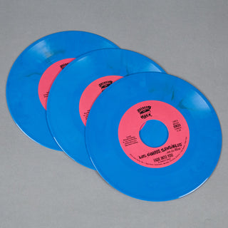 Three translucent blue vinyl records with pink center labels fanned out on a neutral gray background. The front label is readable with the text 'Los Guantes de Sevilla' and 'Fade Into You'.