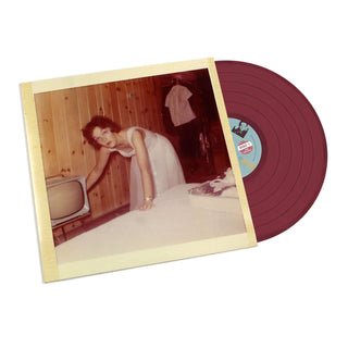 A vinyl record partially covered by a printed photo sleeve, photographed on a plain white background. The record is dark burgundy, and the sleeve shows a vintage-style photo of a woman in a room with wood-paneled walls.