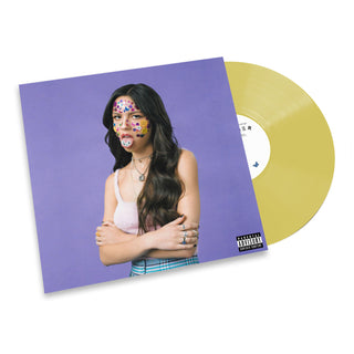 A vinyl record album shown at an angle with its cover sleeve in front. The sleeve features a portrait of a woman with colorful face paint against a lavender background, and the vinyl disc itself is translucent gold.