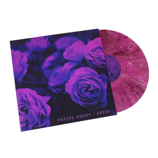 A vinyl record partially pulled from its sleeve, featuring a dark floral cover with purple and blue roses and a pink marbled record.