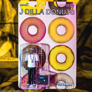 A packaged action figure of J Dilla dressed as a donut, with the text 'J DILLA DONUTS' and 'Super 7' visible on the cardback. The figure is shown in a clear plastic window with accessories, set against a blurred yellow-toned background.