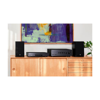 Home theater system on a wooden cabinet with a colorful abstract painting in the background.